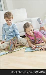 Siblings reading story books on floor in the living room