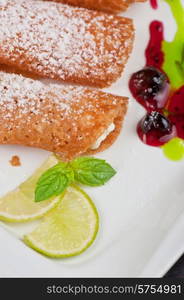 Sicilian cannoli at plate decorated with lime and jam. Sicilian cannoli