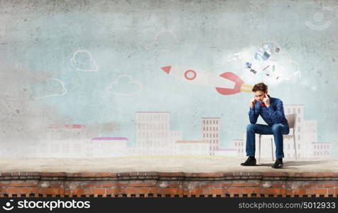 Sick and tired!. Troubled young man sitting in chair outdoors