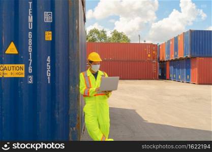 Sick Asian logistic worker engineer man working in cargo container,wearing a face mask in warehouse industry factory site. Export, import concept. Business people. Corona virus and health care concept