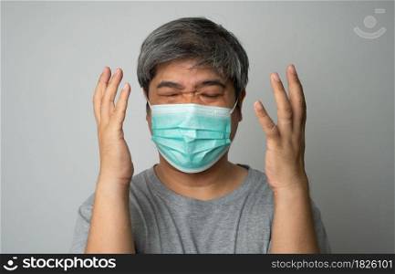 Sick Asian man wearing a medical face mask and Shoulder pain and stress. Concept of protection pandemic coronavirus and respiratory disease