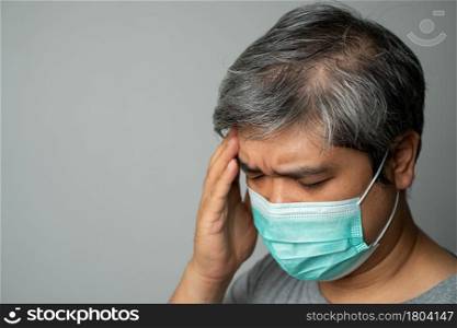 Sick Asian man wearing a medical face mask and Take a hand to hold the headache in the head. Concept of protection pandemic coronavirus and respiratory disease