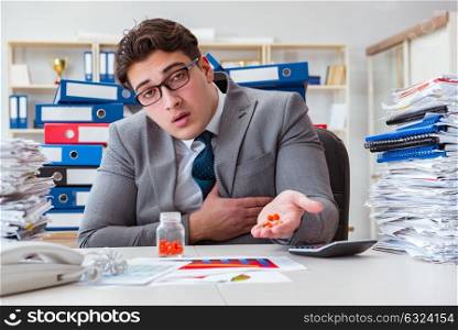 Sick businessman with medicines at work desk