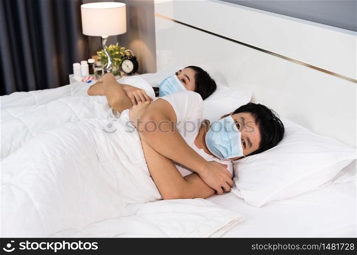sick couple feeling cold on a bed and wearing medical mask for protection coronavirus (covid-19) pandemic