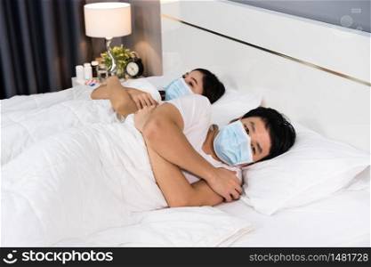 sick couple feeling cold on a bed and wearing medical mask for protection coronavirus (covid-19) pandemic