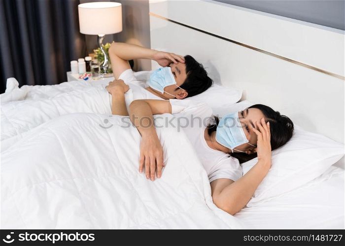 sick couple in medical mask headache and suffering from virus disease and fever in a bed, coronavirus (covid-19) pandemic concept.
