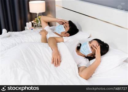 sick couple in medical mask headache and suffering from virus disease and fever in a bed, coronavirus (covid-19) pandemic concept.