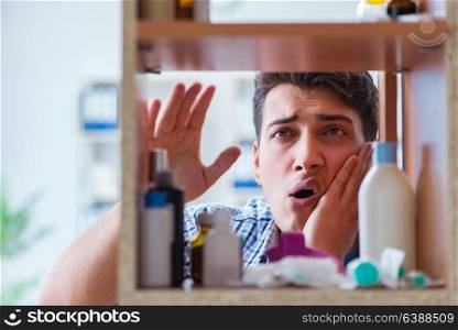 Sick ill man looking for medicines at farmacy shelf