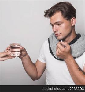 sick man holding glass water from person s hand taking capsule
