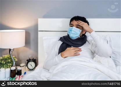 sick man in medical mask is headache and suffering from virus disease and fever in a bed, coronavirus (covid-19) pandemic concept.