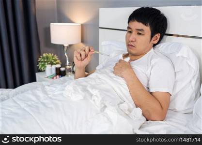 sick man using thermometer to checking his temperature in a bed