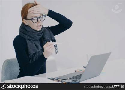 Sick manager at online conference. Young white woman got disease in office. Unwell girl is working in scarf holding thermometer and shocked with her temperature. Worker feels ill and has fever.. Sick manager at online conference. Unwell girl is shocked with her temperature and fever.