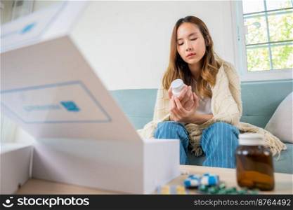 Sick people reading information medicine label pills, female with flu virus, Asian young woman reading ingredient and hold bottle drug on sofa in living room at home, Healthcare and medicine concept