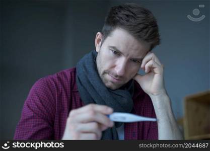 Sick unhealthy German man office worker looking at thermometer, suffer of flu influenza while sitting at his workplace, Ill male employee measuring body temperature at work. Sick unhealthy German man office worker looking at thermometer, suffer of flu influenza