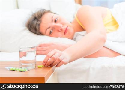 sick woman in bed reaching for pills