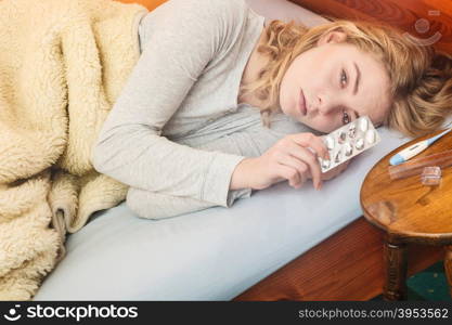 Sick woman in bed taking pills. Health treatment.. Sick woman laying in bed taking tablets pills. Ill girl caught cold flu. Thermometer on table. Health care treatment.