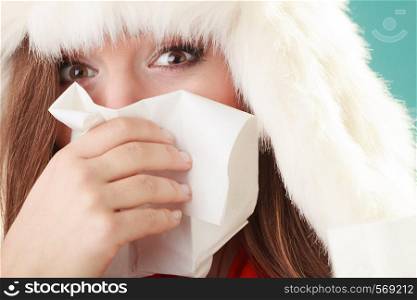 Sick woman in fur hat sneezing in tissue. Ill girl caught winter cold flu in studio on green.