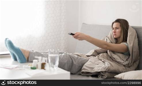 sick woman sitting bed watching tv