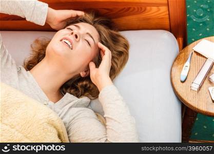 Sick woman suffering from headache pain.. Sick woman suffering from headache pain. Ill girl laying in bed caught cold. Thermometer and pills on table.