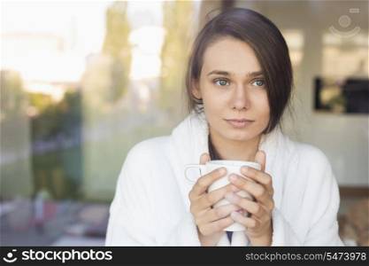 Sick young woman holding coffee mug at home
