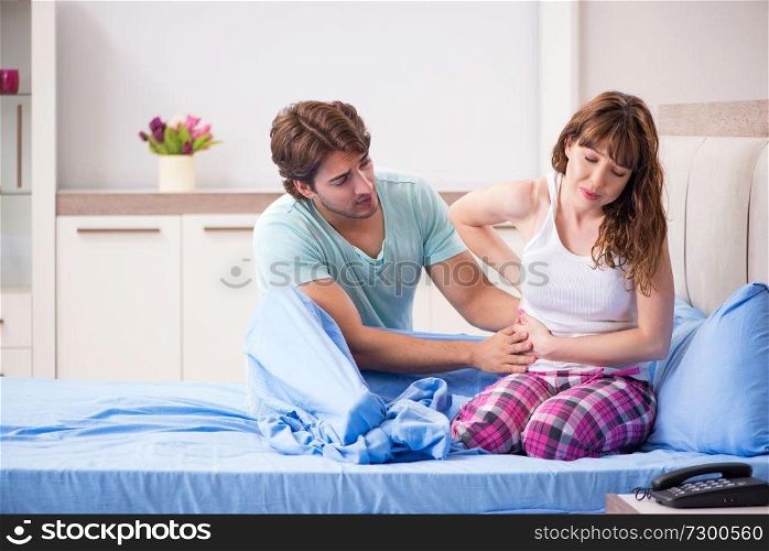 Sick young woman with husband in the bedroom 