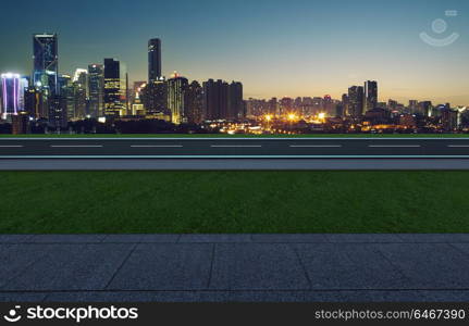 Side angle view empty asphalt road with grass ,stone marble floor and city skyline background . Mixed media .