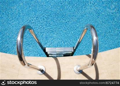 Side of a swimming pool with chrome stairs