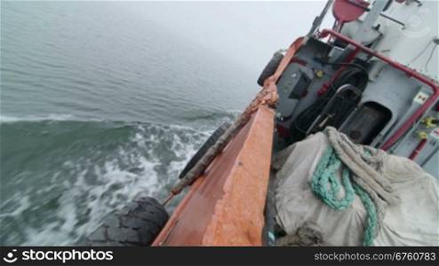 Side of commercial fishing boat in the foggy sea of Azov