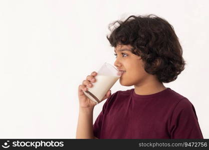 SIDE PORTRAIT OF A HAPPY BOY HOLDING A GLASS OF MILK