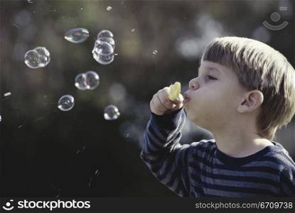 Side profile of a boy blowing bubbles