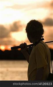 Side profile of a boy carrying a fishing rod