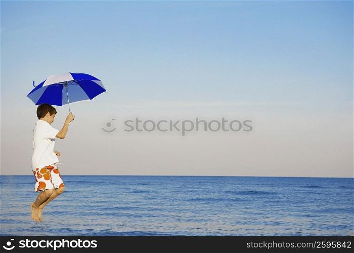 Side profile of a boy jumping with an umbrella