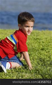 Side profile of a boy kneeling on a lawn