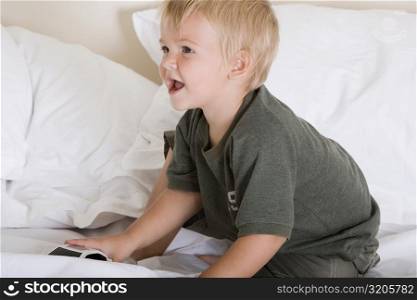 Side profile of a boy playing with a toy car on a bed