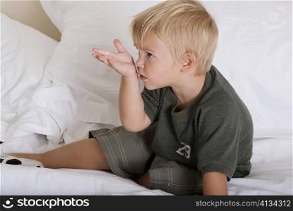 Side profile of a boy sitting on a bed