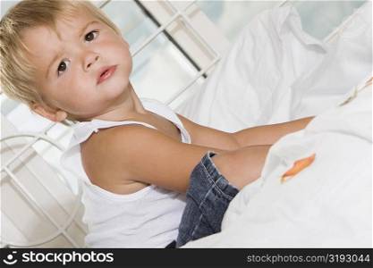 Side profile of a boy sitting on the bed