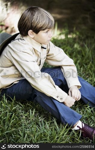 Side profile of a boy sitting on the grass