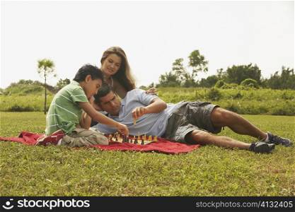 Side profile of a boy sitting with his parents and playing chess