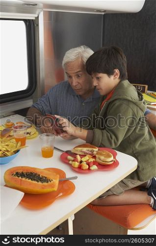 Side profile of a boy teaching his grandfather how to use a mobile phone