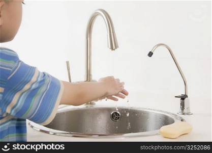 Side profile of a boy washing his hand
