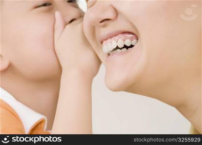 Side profile of a boy whispering into his mother&acute;s ear