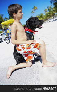 Side profile of a boy with a dog on the beach