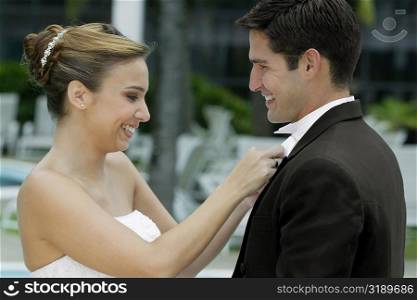 Side profile of a bride adjusting her groom&acute;s bow tie