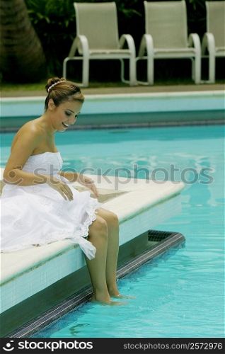 Side profile of a bride sitting at the poolside and smiling