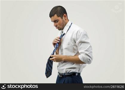 Side profile of a businessman adjusting his tie