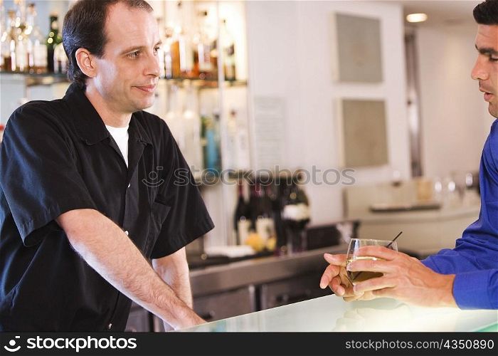 Side profile of a businessman and a bartender at a bar counter