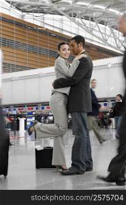 Side profile of a businessman and a businesswoman hugging each other at an airport