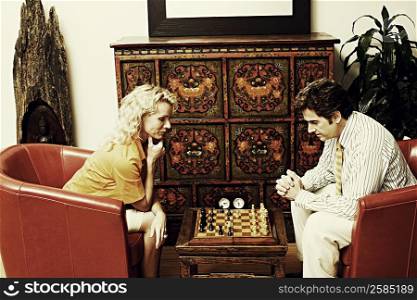 Side profile of a businessman and a businesswoman playing chess