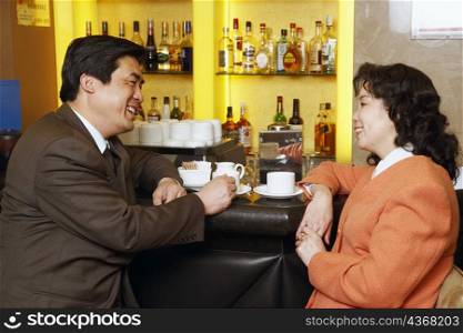Side profile of a businessman and a businesswoman sitting at a bar counter