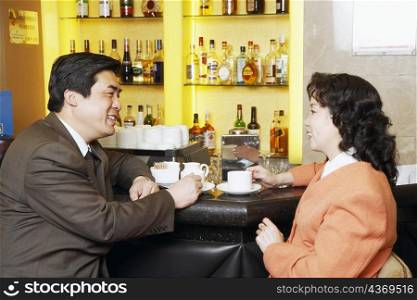 Side profile of a businessman and a businesswoman sitting at a bar counter